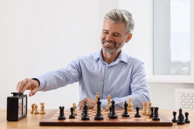 Photo of Man turning on chess clock during tournament at table indoors