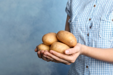 Photo of Person holding handful of fresh organic potatoes on color background