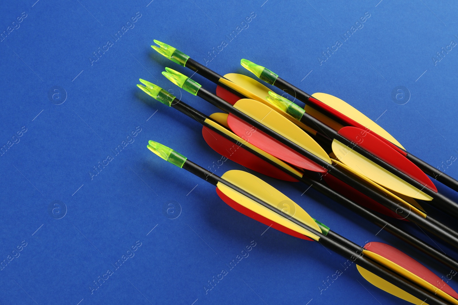 Photo of Many arrows on blue background, flat lay. Archery sport equipment