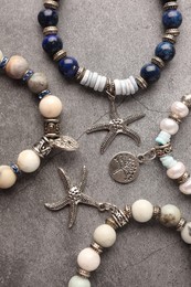 Different beautiful bracelets with gemstones on grey background, flat lay