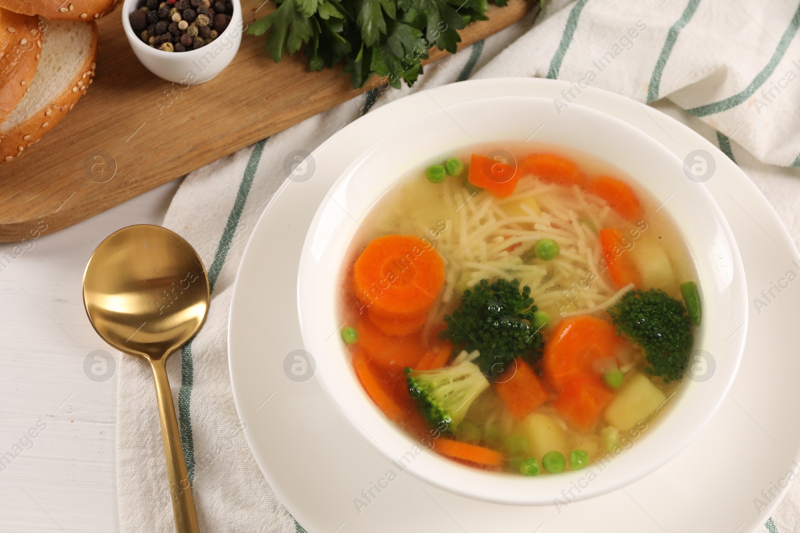 Photo of Delicious vegetable soup with noodles served on white wooden table, above view