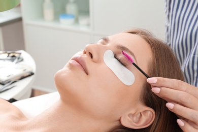 Photo of Young woman undergoing eyelash extensions procedure, closeup