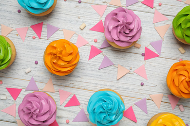 Photo of Colorful birthday cupcakes on white wooden table, flat lay
