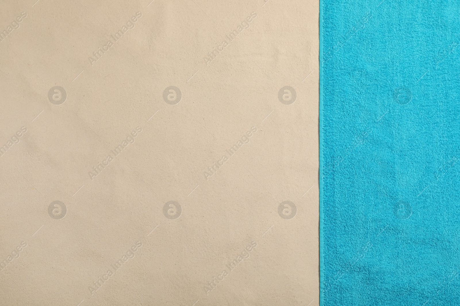 Photo of Light blue beach towel on sand, top view. Space for text