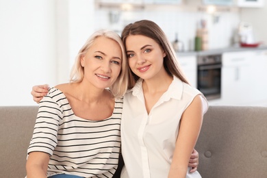 Portrait of mature woman and her daughter on sofa in living room