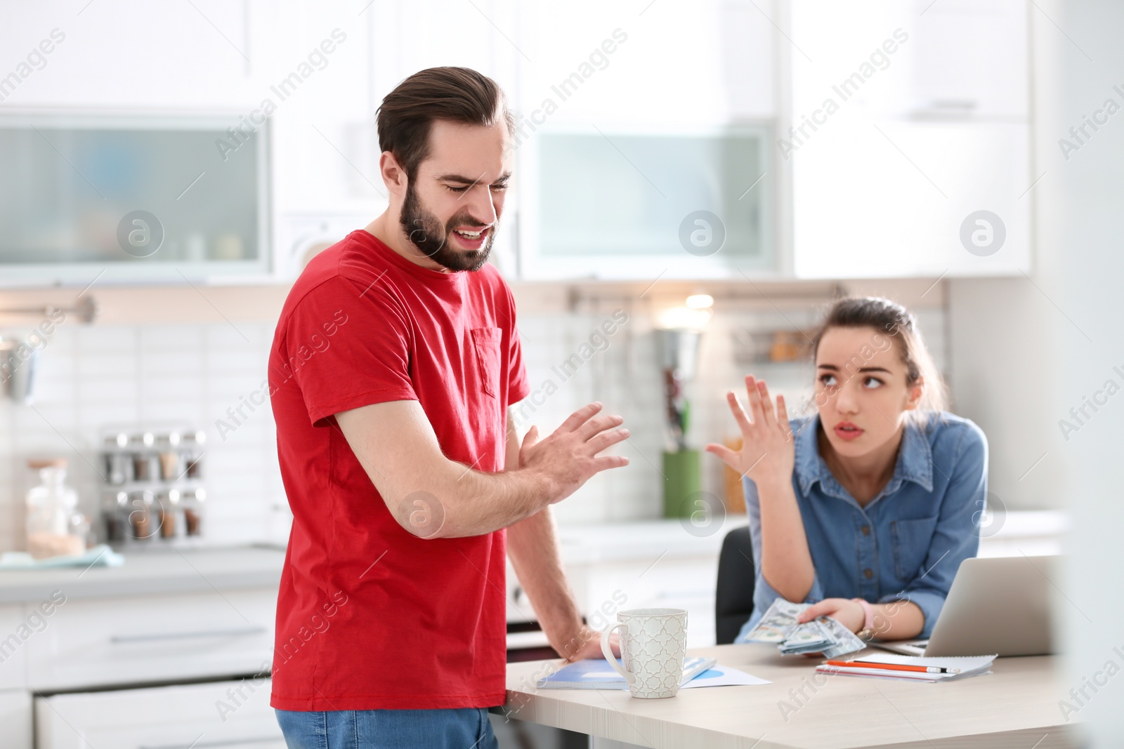 Photo of Young couple having argument about family budget in kitchen