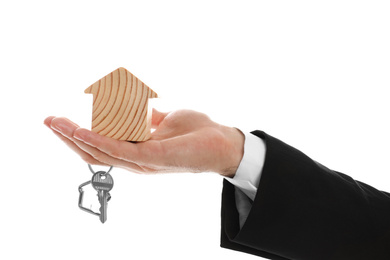 Real estate agent holding house figure and key on white background, closeup