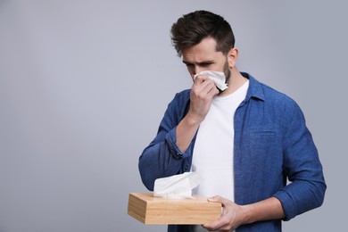 Photo of Man blowing nose on grey background, space for text. Cold symptoms