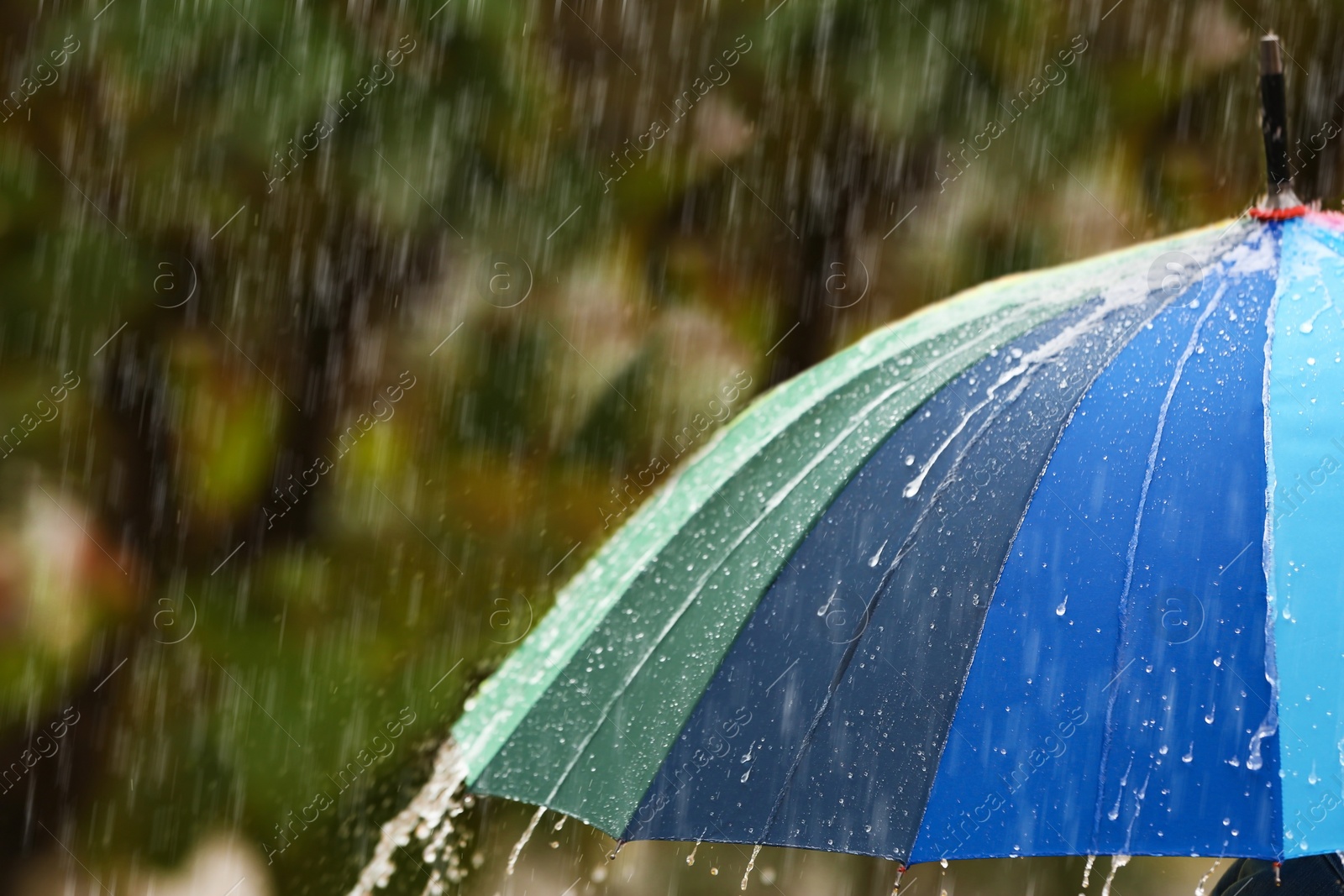 Photo of Bright umbrella under rain on street, closeup