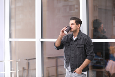 Handsome man drinking coffee near window. Space for text