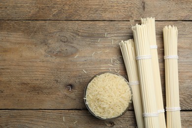 Photo of Rice and raw noodles on wooden table, flat lay. Space for text