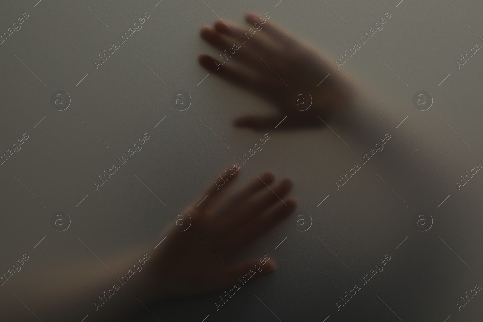 Photo of Silhouette of creepy ghost behind glass against grey background, closeup