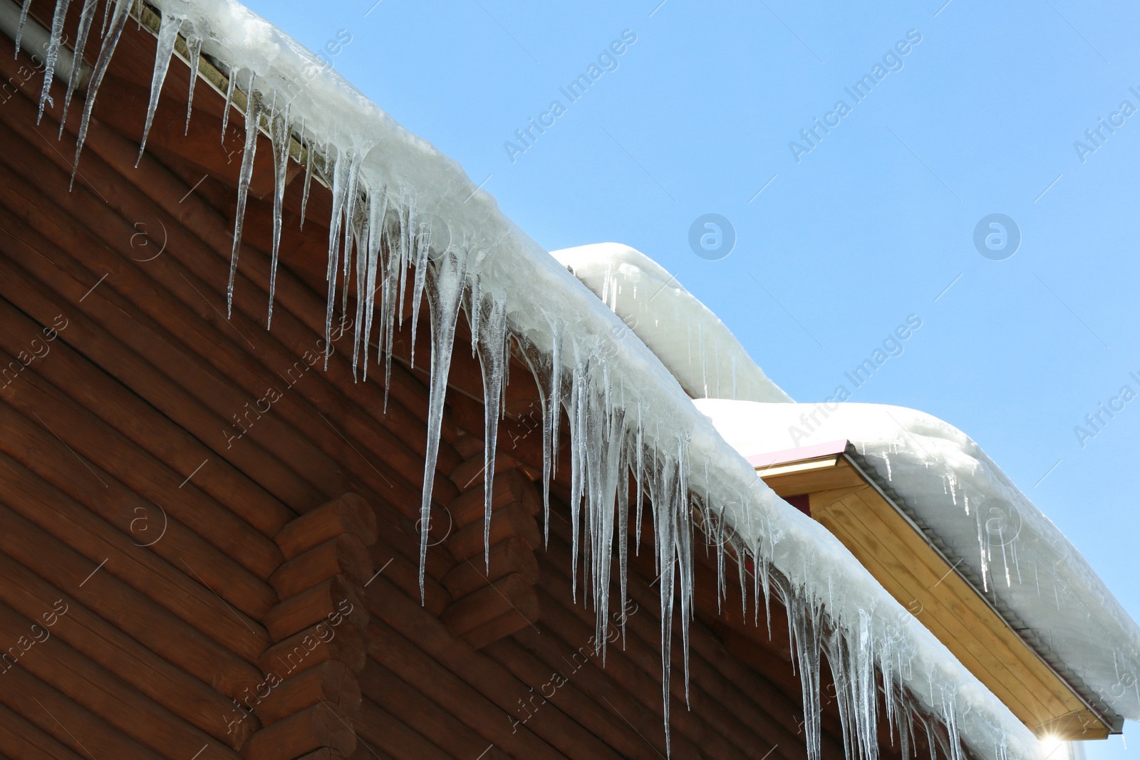 Photo of House with icicles on roof, low angle view. Winter season