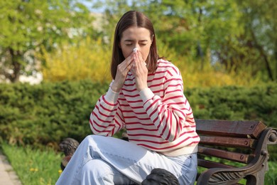 Photo of Woman with napkin suffering from seasonal allergy on bench in park