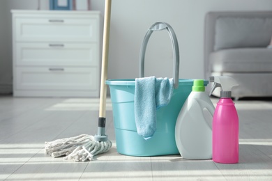 Photo of Bucket, mop and cleaning supplies on floor indoors