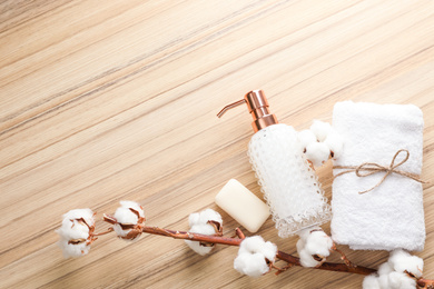 Flat lay composition with soap dispenser and cotton flowers on wooden background. Space for text