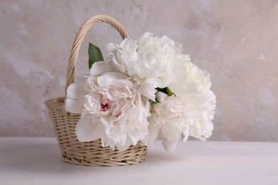 Photo of Beautiful peonies in wicker basket on white table
