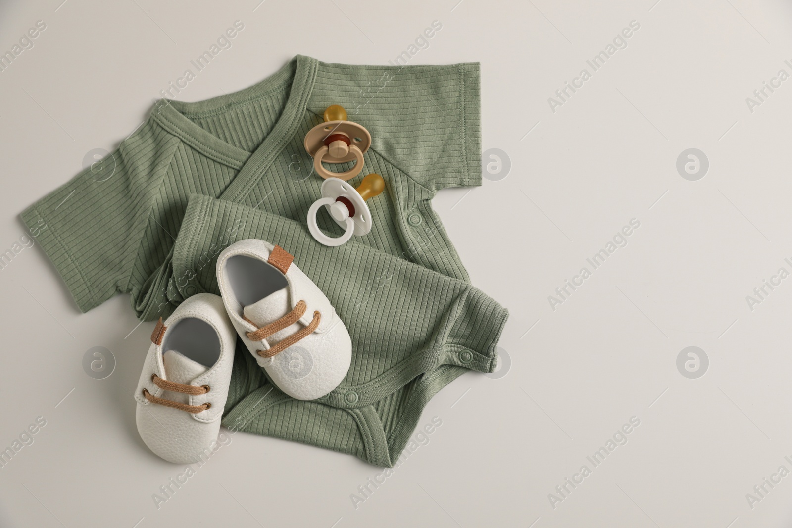 Photo of Baby clothes, shoes and pacifiers on white background, flat lay. Space for text