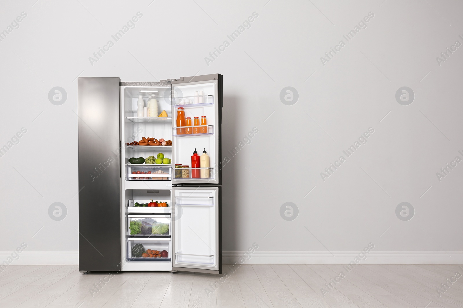 Photo of Open refrigerator filled with food indoors, space for text