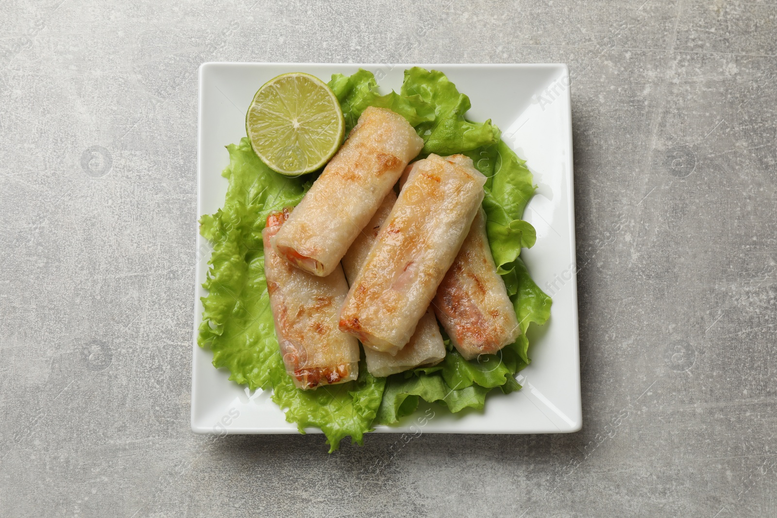 Photo of Delicious fried spring rolls on grey table, top view