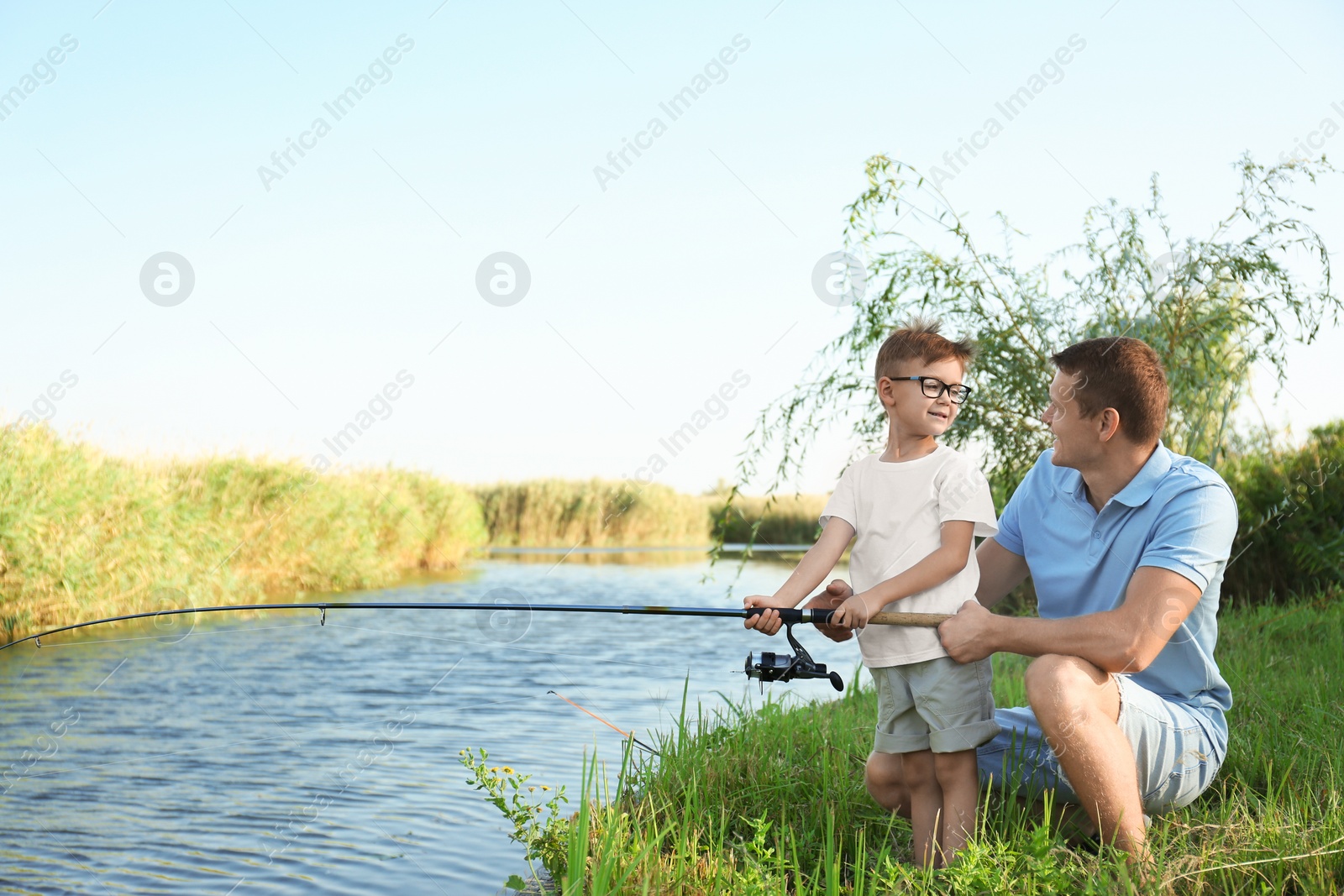 Photo of Dad and son fishing together on sunny day