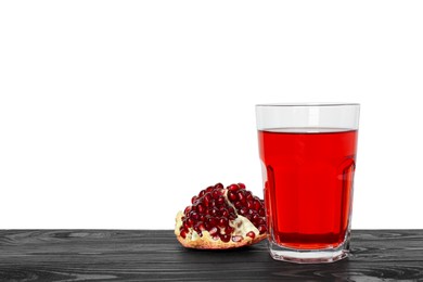 Photo of Refreshing pomegranate juice in glass and fruit on black wooden table against white background. Space for text