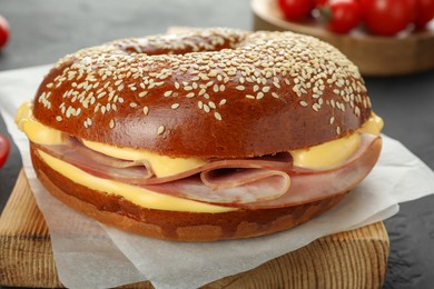 Photo of Delicious bagel with ham and cheese on grey table, closeup
