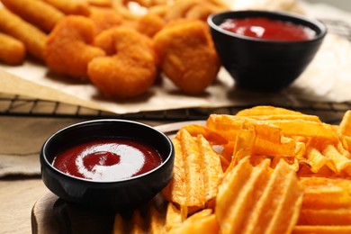 Bowls with tasty ketchup and snacks on table, selective focus