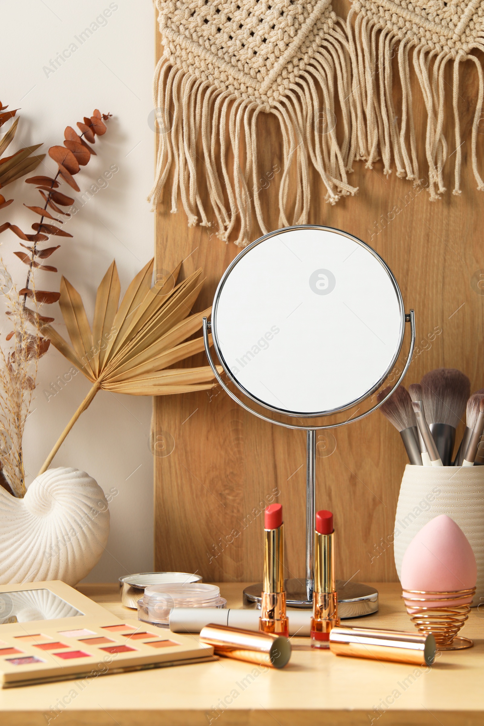 Photo of Makeup products, mirror and decor on wooden dressing table indoors