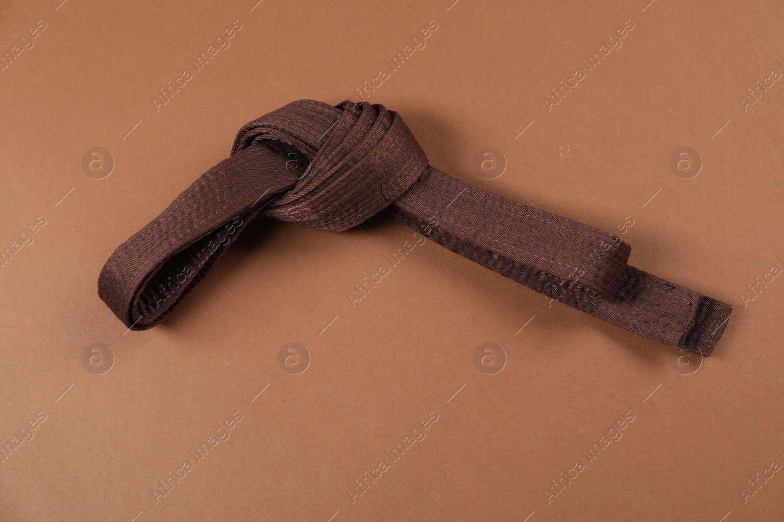 Photo of Karate belt on brown background. Martial arts uniform