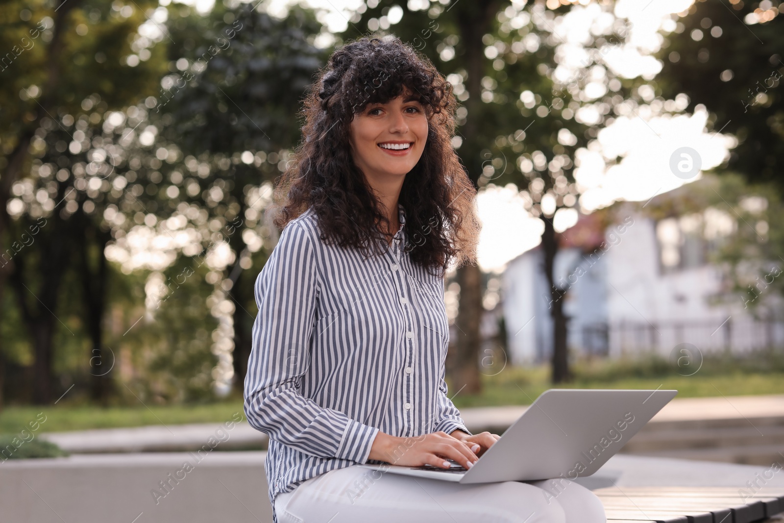 Photo of Happy young woman using modern laptop outdoors