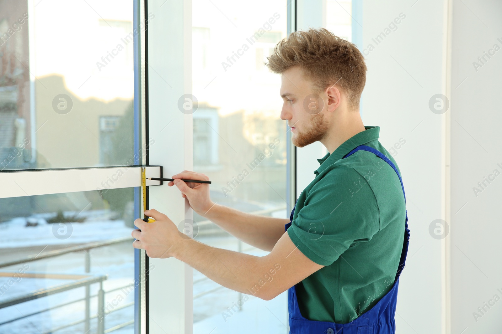 Photo of Service man measuring window for installation indoors