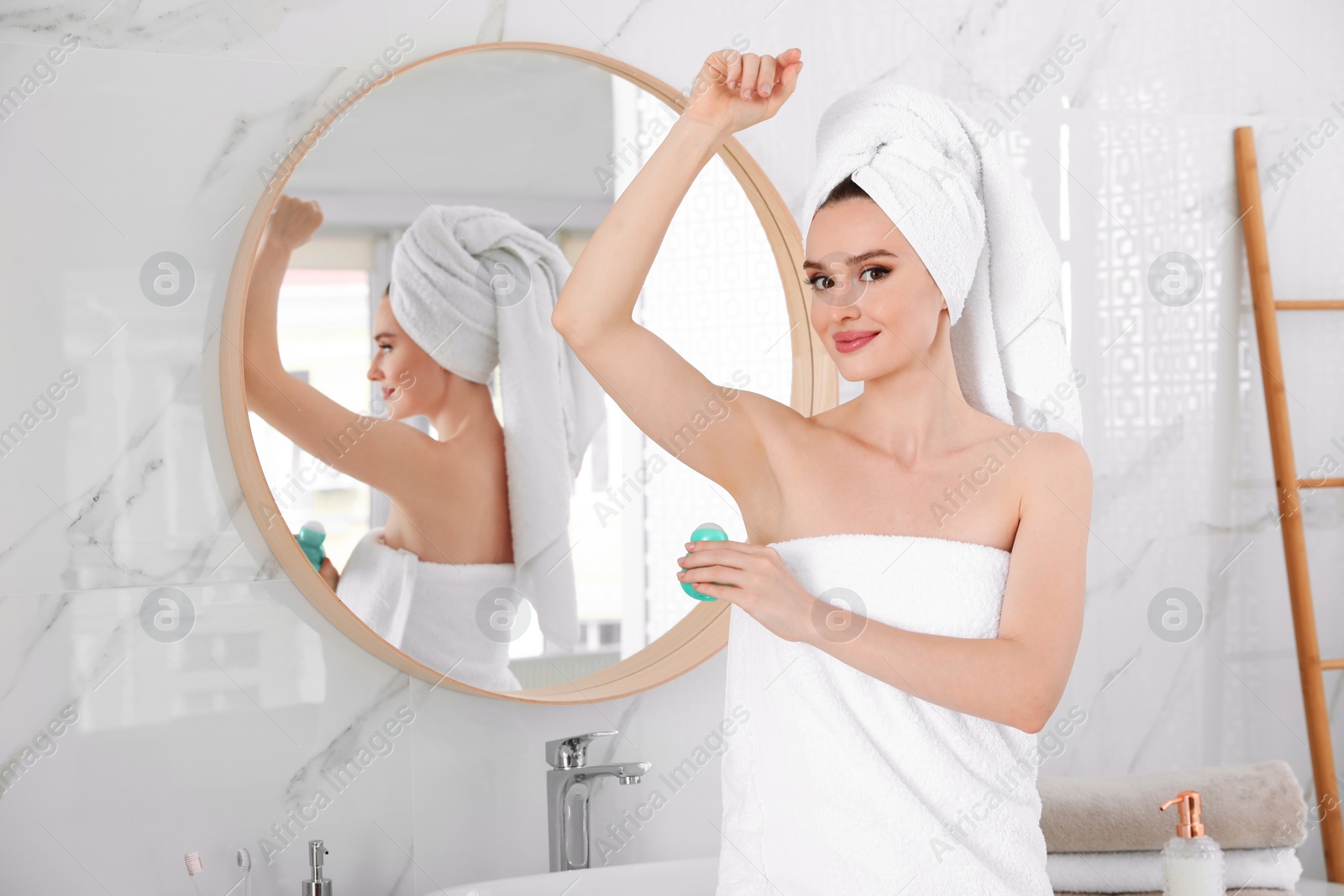 Photo of Beautiful young woman applying deodorant after shower in bathroom