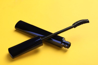 Photo of Mascara for eyelashes on yellow background, closeup. Makeup product