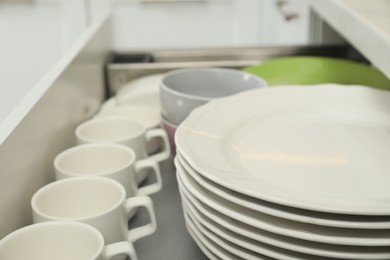 Clean plates, bowls and cups in drawer indoors, closeup