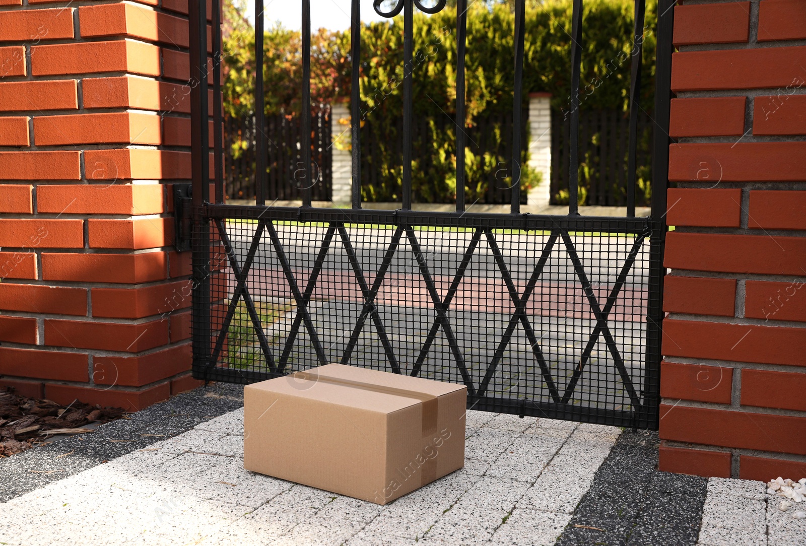 Photo of Cardboard boxes near front gates outdoors. Parcel delivery service