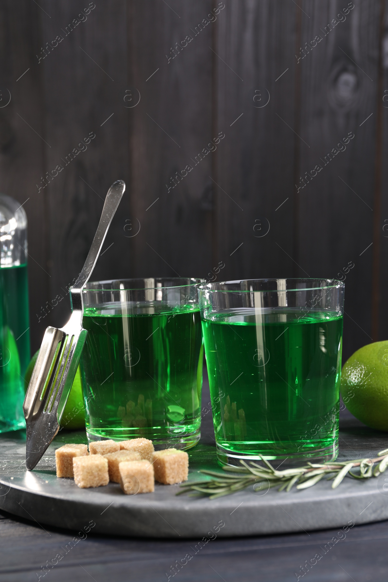 Photo of Absinthe in glasses, rosemary, brown sugar and spoon on table. Alcoholic drink