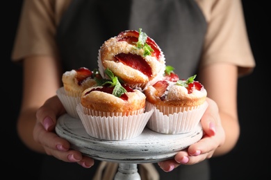 Woman with delicious plum cupcakes on black background, closeup