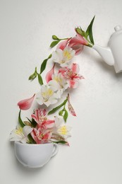 Composition with beautiful flowers, cup and teapot on light background, top view