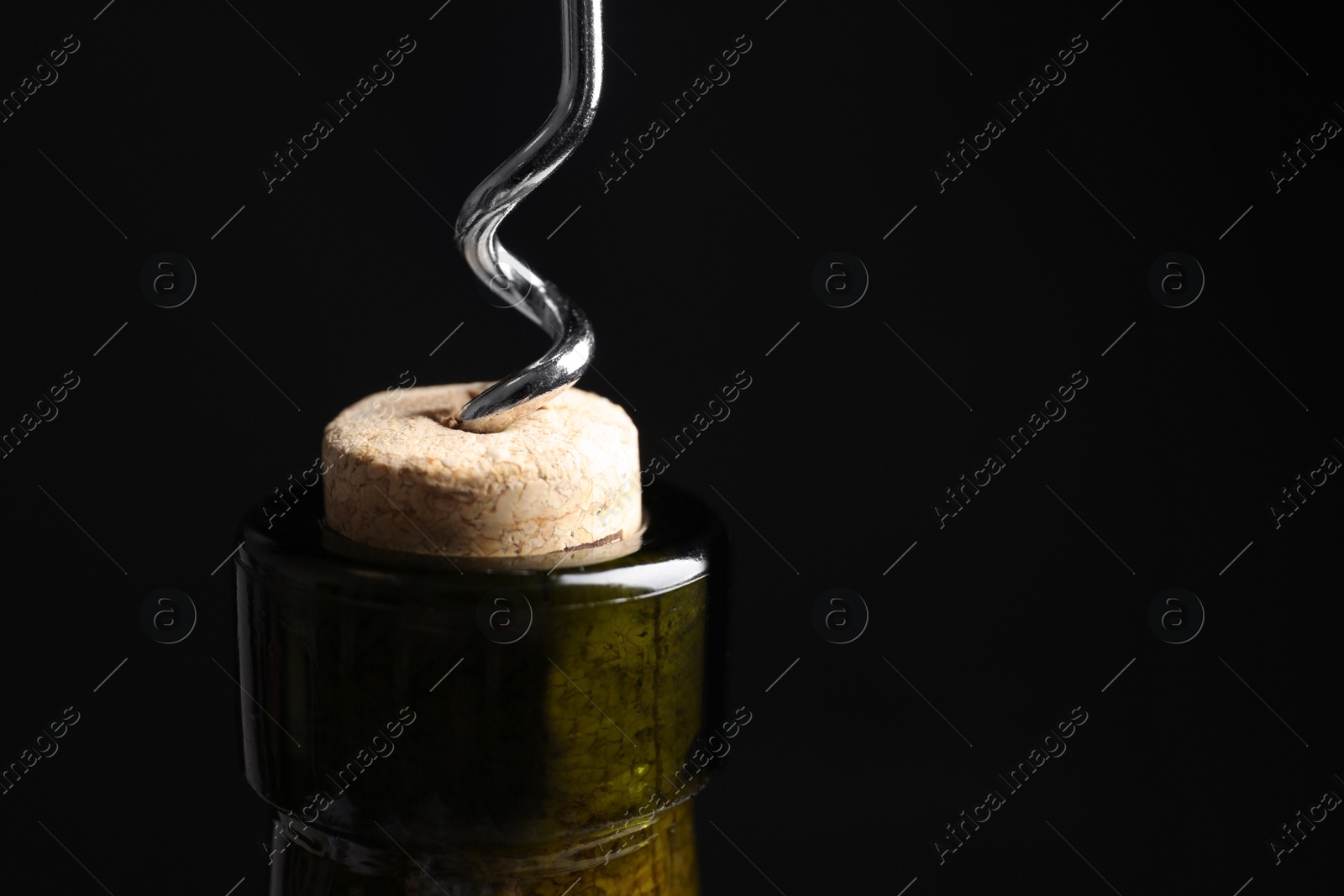 Photo of Opening wine bottle with corkscrew on black background, closeup. Space for text