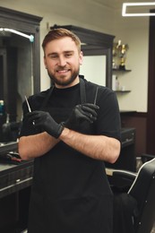 Happy hairdresser with professional tools in barbershop