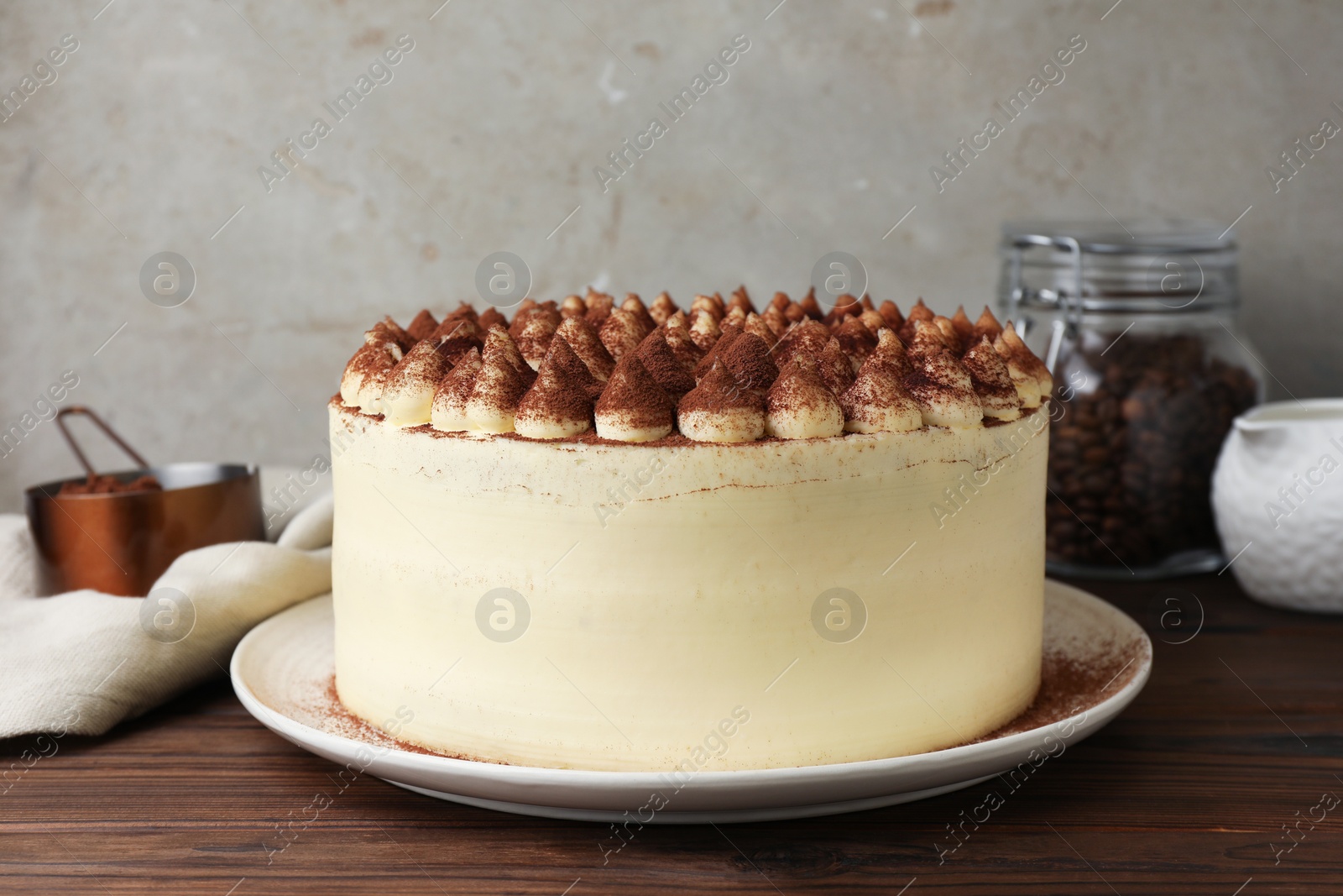 Photo of Delicious tiramisu cake with cocoa powder on wooden table