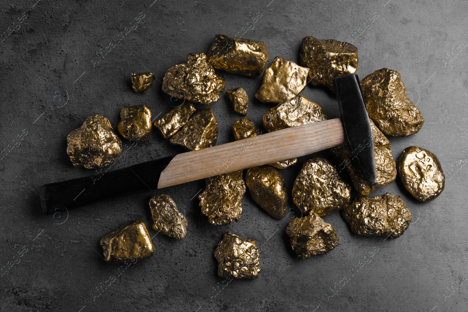 Photo of Gold nuggets and hammer on grey table, flat lay