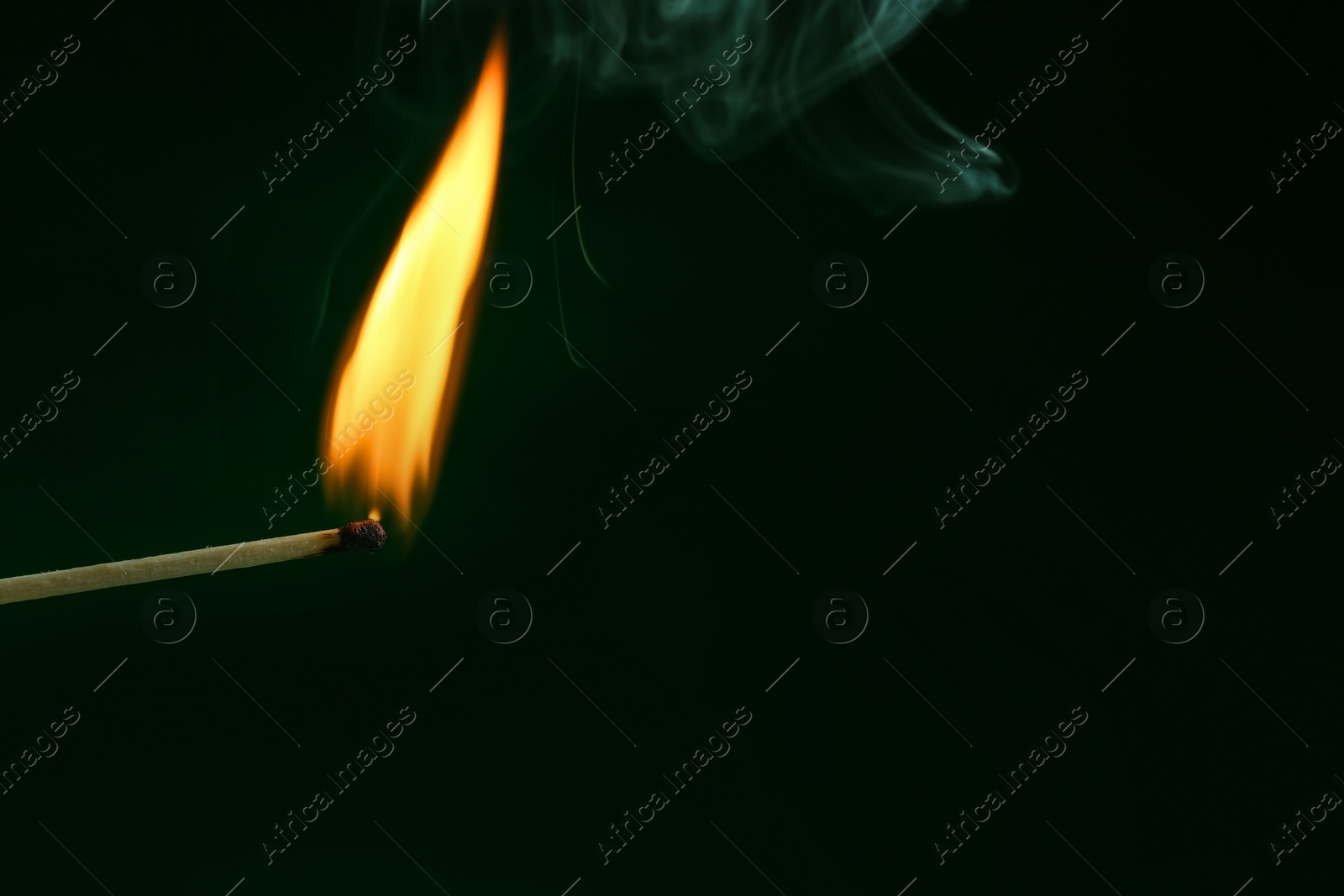 Photo of Burning matchstick on color background, closeup. Space for text