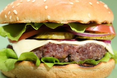 Photo of Burger with delicious patty on green background, closeup