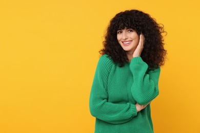 Happy young woman in stylish green sweater on yellow background, space for text