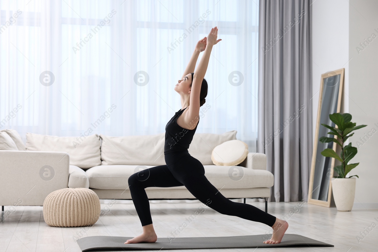Photo of Girl practicing crescent asana on yoga mat at home. High lunge pose