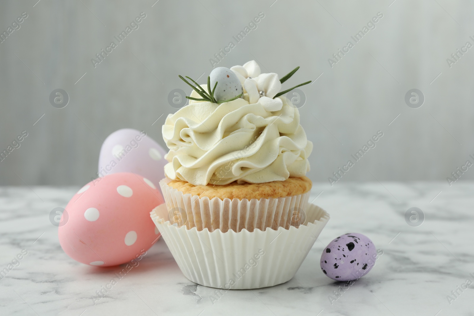 Photo of Tasty Easter cupcake with vanilla cream and eggs on white marble table