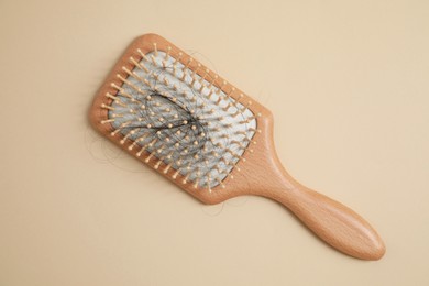 Photo of Wooden brush with lost hair on beige background, top view