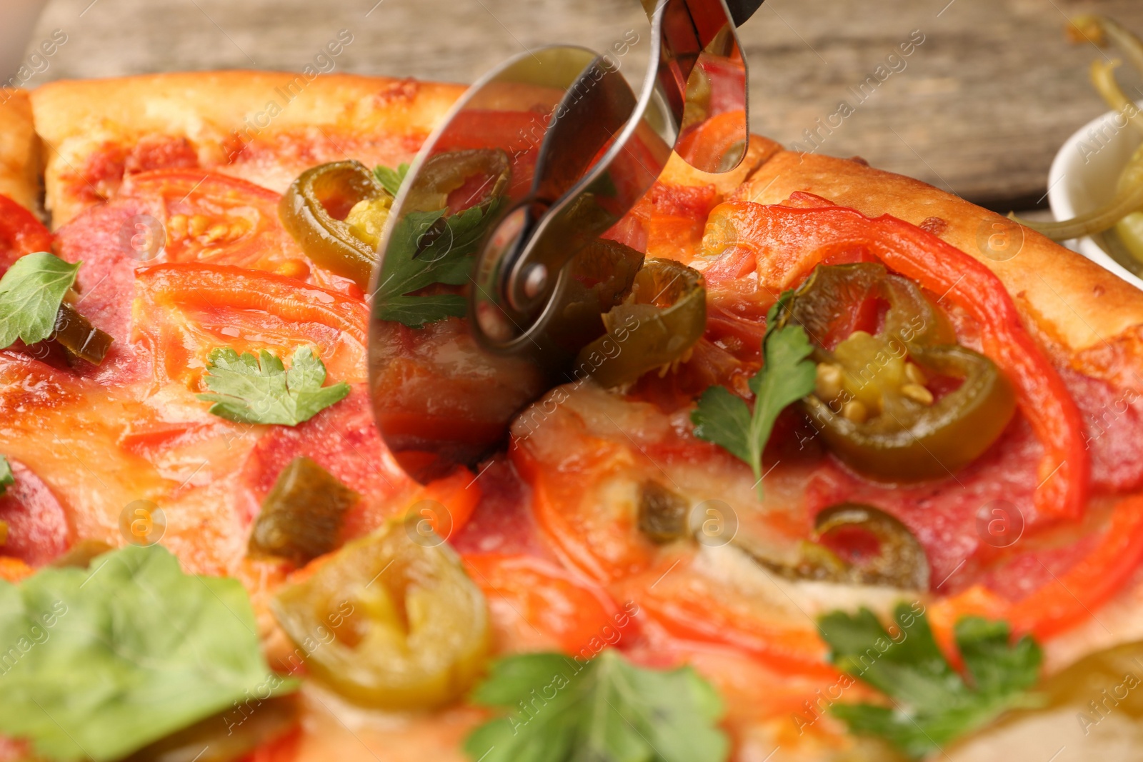 Photo of Cutting delicious pizza Diablo at table, closeup